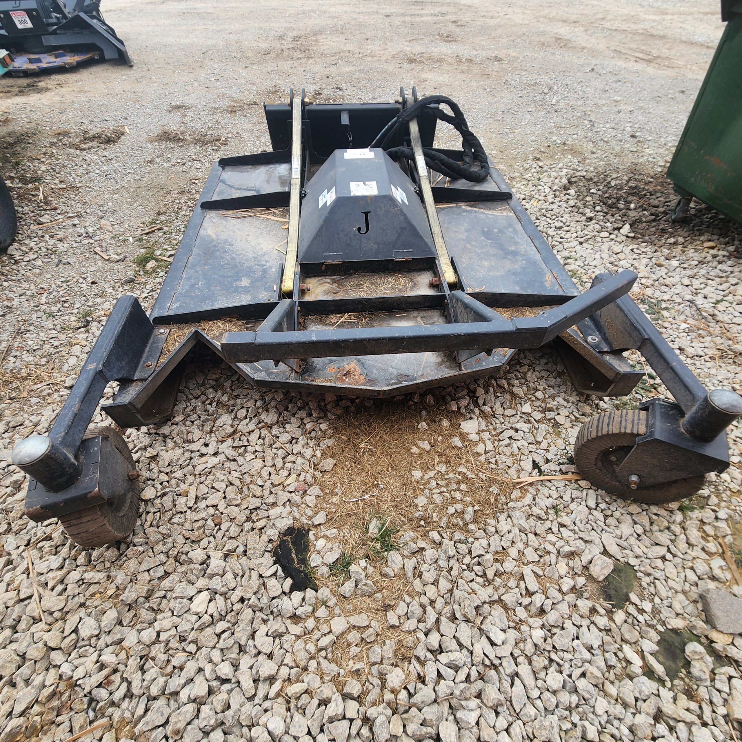 Heavy-duty 6ft brush mower attachment on gravel ground. Features metal frame, multiple blades, large casters.